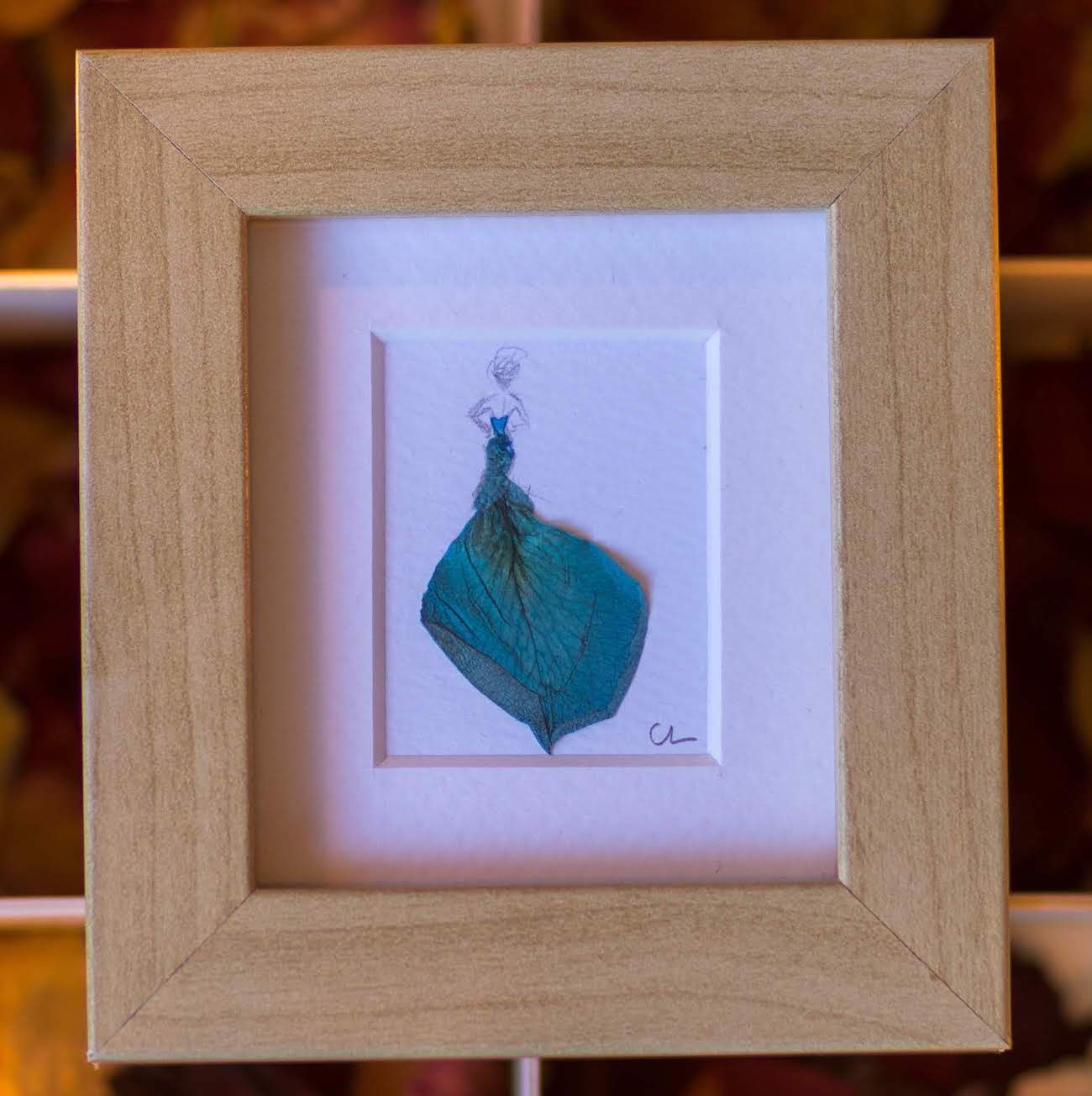 Created from a single rose petal, this art piece portrays a figure in a blue dress, with a sense of flow and motion that captures the energy and vibrancy of the woman wearing it.